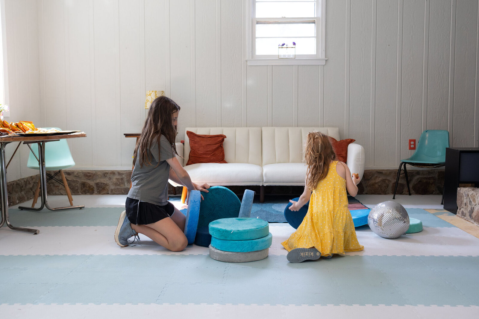 Two learners moving foam blocks and pillows across the studio floor.
